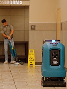 cleaning staff using Tenant T2 walk behind floor scrubber to clean department store entry way