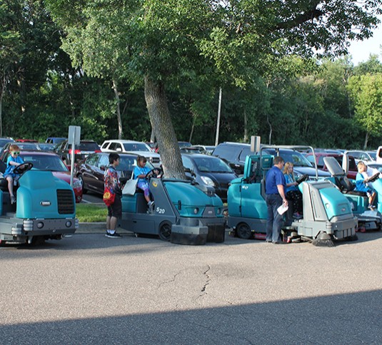 Children sitting on Tennant M17 sweeper-scrubber and S20 sweeper