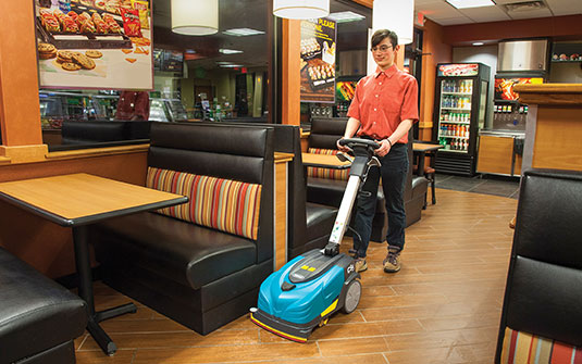 cleaning staff using CS5 walk-behind floor scrubber in convenience store to clean floor