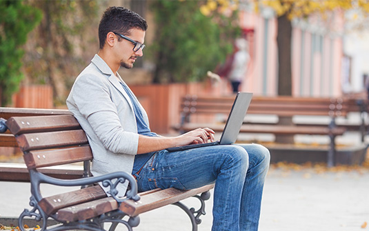 remote worker on laptop outside on bench