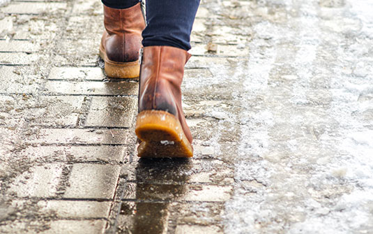 a person wearing snow boots walking on an icy pavement