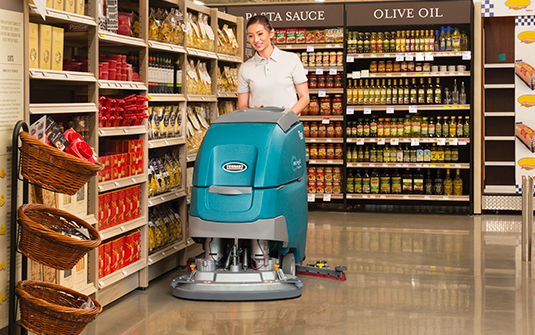 A worker maintains a polished concrete floor with an auto scrubber.