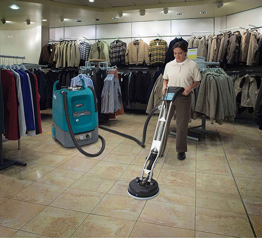 un equipo de mantenimiento limpia los azulejos en una tienda de ropa usando la máquina de limpieza para superficies múltiples Tennant Q12 