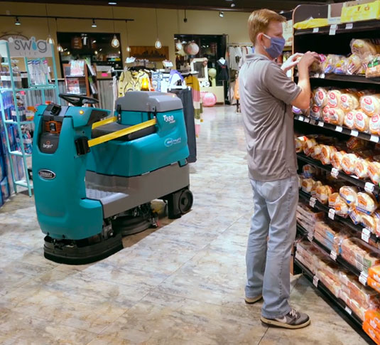 Una restregadora robotizada de pisos Tennant limpiando un pasillo en un supermercado