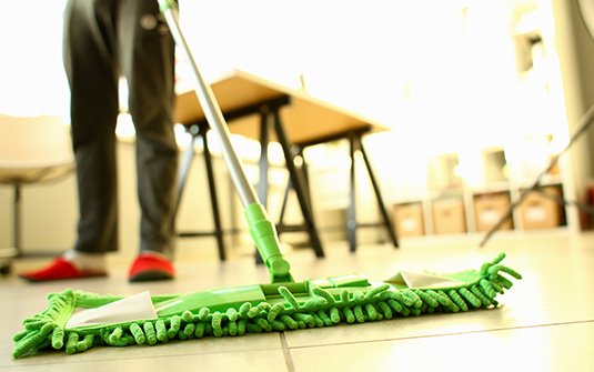 scopettone verde per pulizia a secco dei pavimenti in laminato in azione